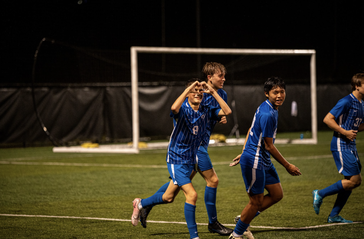 Luis McVicker (11) holds up a heart to the OZONE after scoring.